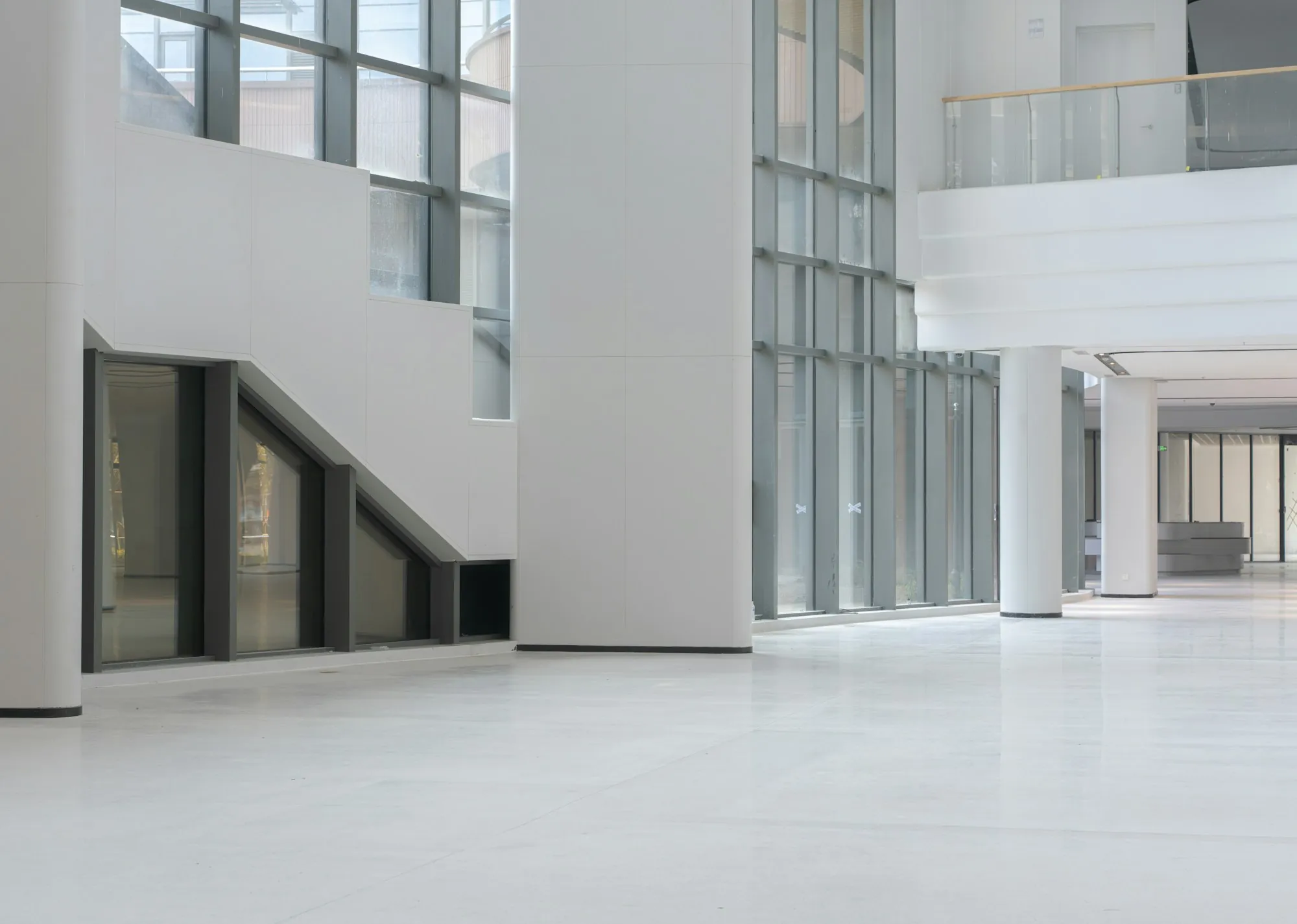 Clean white office interior with a glass staircase and tile floor