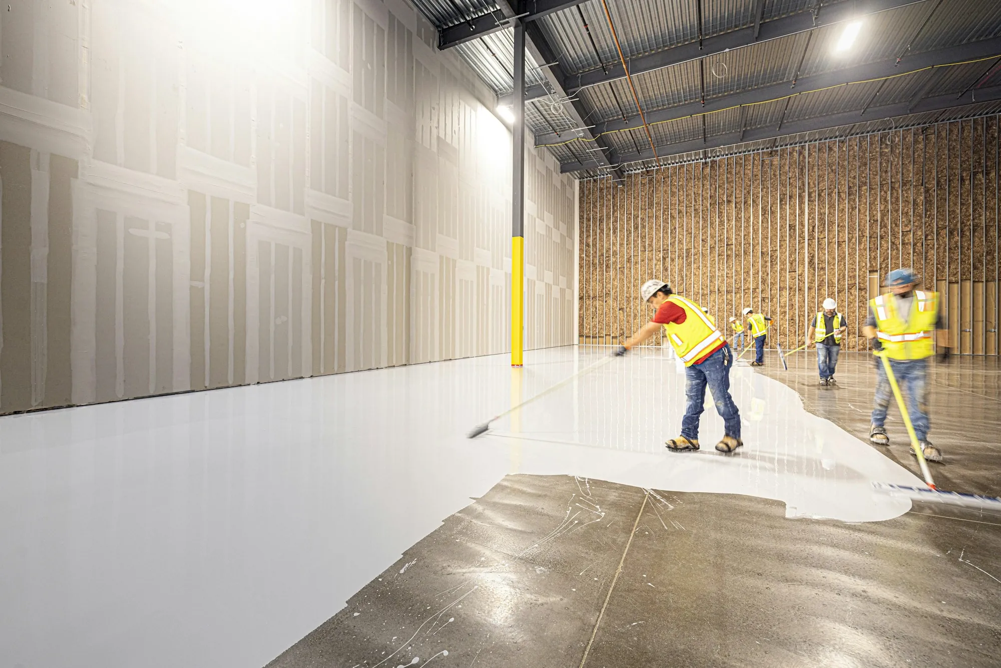 Crew applying floor coating in a large warehouse